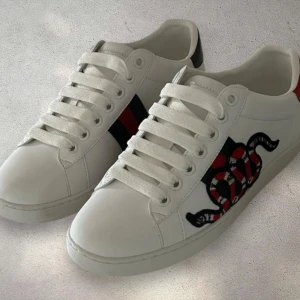 Gucci ace - Riktigt snygga och populära Gucci ace skor med en riktigt snygg design på sidan. Skorna är använda max 5 gånger och ser nästan forfarande ut som nya bara att sulan är lite smutsig. Skorna är i storlek 35 men kan passa 36 också skulle jag tro! Om ni är intresserade är ni välkomna att fråga hur mycket som helst angående skorna. Det ingår ingen låda. Jag har tyvärr inte heller något kvitto med skorna eftersom de är köpta för längesedan men inte varit använda!