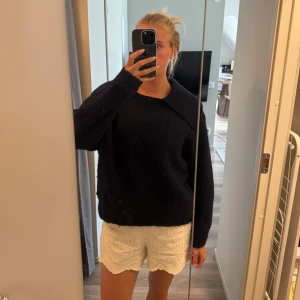 Mörkblå stickad tröja med krage - Mysig mörkblå stickad tröja med bred krage och avslappnad passform. Tröjan har långa ärmar och är perfekt för kyligare dagar. Enkel och stilren design som funkar till många olika outfits.