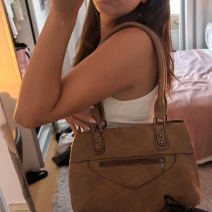 Brun vintage väska - Säljer en vintage väska med flätad detalj på framsidan och flera fack med dragskejdan. Vet inte vilket märke de är❤️ 