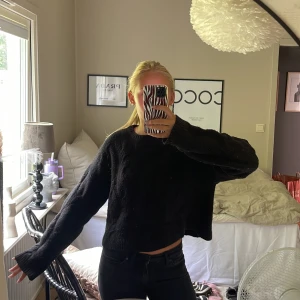 Svart stickad tröja med kabelmönster - Mysig svart stickad tröja med kabelstickat mönster och långa ärmar. Tröjan har en lite loose passform och ribbade muddar vid ärmslut och nederkant. 