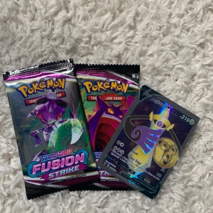 Pokémon Sword & Shield Fusion Strike Booster Packs + Aegislash V - Två oöppnade Pokémon Fusion Strike booster packs och ett holografiskt Aegislash V-kort. Perfekt för dig som vill utöka din samling eller jaga nya favoriter! Passar både samlare och spelare som älskar Pokémon. Ej original!