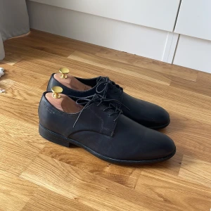 Svarta skinnskor från Vagabond - Klassiska svarta skinnskor från Vagabond med rund tå och snörning. Snygg minimalistisk design med platt sula, perfekta till kostym eller dressade outfits. Skorna är i skinn och har diskreta sömmar för en clean look.