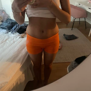 Orange tighta träningsshorts - Säljer ett par knallorange tighta träningsshorts.De är midwaist och har en kort passform som sitter riktigt snyggt på kroppen. Perfekta för gymmet eller danspasset. Materialet är stretchigt och följsamt för maximal rörelsefrihet.