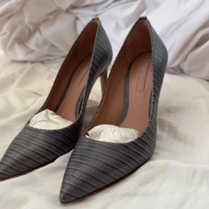 Grå klackar med reptilmönster från BOSS - något använda BOSS klackar med 5 cm klack i super snyggt mönster och nypris är 3500kr❤️ hela paketet är med dvs allt ingår hugo boss lappen och en påse och boss kartongen