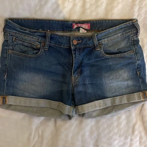 Blå jeansshorts med uppvikta ben - Snygga blå jeansshorts från Esprit med klassisk femficksdesign och uppvikta ben. Shortsen har coola detaljer som kopparfärgade knappar och unika bakfickor med lock och knapp. Perfekta för varma dagar och enkel att matcha med allt. Midjemåttet är 44cm rakt över💖