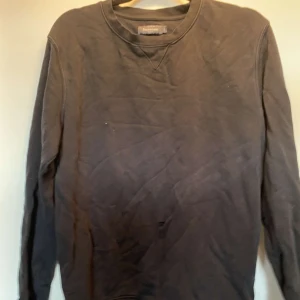 Svart sweatshirt från Dressmann L - En svart sweatshirt från Dressmann i storlek L. Tröjan har rund halsringning, långa ärmar och är tillverkad i mjuk bomull. Enkel och stilren design utan tryck eller mönster, perfekt för en chill och avslappnad look.