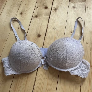 Vit spets-bh med strass från Censored - Säljer en vit bh från Censored med vacker spets och glittrande strassdetaljer på kuporna. Bh:n har justerbara axelband och en liten rosett framtill. Perfekt för dig som gillar romantiska och feminina detaljer.