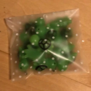 Pack med Gröna sköldpadds berlocker till smycken - Säljer ett pack med 12 st söta gröna sköldpaddshängen i plast, perfekta att använda till armband, halsband eller örhängen. Hängena har svart mönster på skalet och en liten ögla i metall för enkel fastsättning. Perfekt för dig som vill skapa egna smycken med en gullig touch.