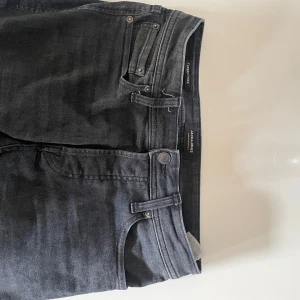 Svarta tapered jeans Jack & Jones - Snygga svarta jeans från Jack & Jones med tapered fit och klassisk femficksdesign. Jeansen har en mörk tvätt och raka bakfickor med diskreta sömmar. Perfekta för dig som gillar en stilren look med bekväm passform.bud tas