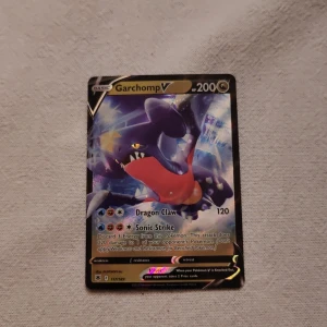 Garchomp V - Coolt Pokémonkort med Garchomp V! Perfekt för dig som samlar eller spelar Pokémon TCG. Kortet har snyggt holografiskt motiv och kraftfulla attacker som Dragon Claw och Sonic Strike. Ett måste för alla Pokémon-fans och samlare!