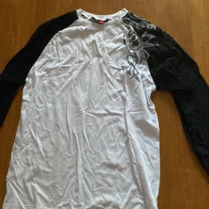 Svartvit långärmad tröja One Way - Säljer en svartvit långärmad tröja från One Way i storlek M. Tröjan har svarta ärmar och vit kropp med grått tribal-inspirerat tryck över axeln. Skön passform och tillverkad i mjuk bomull.