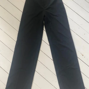 Svarta kostymbyxor Pull&Bear - Svarta kostymbyxor från Pull&Bear i klassisk rak modell. Byxorna har hög midja och vida ben för en clean och stilren look. Köpta i spanien storleken är 32 men känns som S skulle jag säga!