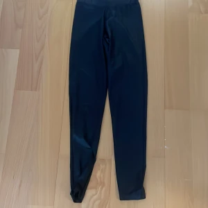 Svarta leggings från Pieces - Snygga svarta leggings från Pieces med glansig finish. De har en tight passform och är perfekta för dig som gillar en stilren look. Materialet är stretchigt och känns mjukt mot huden, vilket gör dem riktigt bekväma att bära hela dagen.