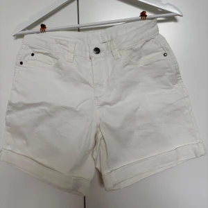 Vita shorts från Kaffe - Snygga vita jeansshorts från Kaffe i storlek S. Köpta för några år sedan men har inte använt dem och därför säljer jag dem.           Midjemått rakt över: 35,5cm                                      Innerbensmått: 13cm                                               Hela benet: 37cm                                                    Skriv till mig om ni har frågor.