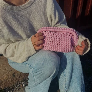 Rosa handvirkad clutch/handväska - Säljer en rosa handvirkad clutch / handväska. Väskan är i ett mjukt garn och är väldigt rymlig! Kan bäras i handen som en clutch eller bäras i handtaget.  