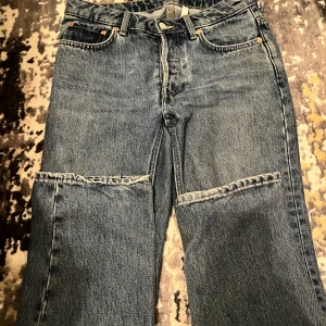 Blå jeans från Weekday - Snygga blå jeans från Weekday med klassisk femficksdesign och knappgylf. De har en rak passform och är perfekta för en avslappnad stil. Tillverkade i slitstarkt denim. Storlek W27 L32. Passar från storlek 36-38