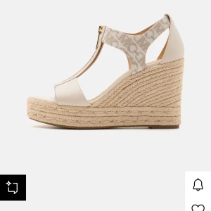 Beige kilklackssandaler - Michael Kors 38,5 i storlek, nya då jag endast använt dem 2 gånger. Snygga beige sandaler med kilklack och öppen tå. Sandalerna har en dragkedja framtill och en flätad sula som ger en somrig känsla. 