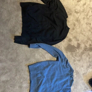 Svart och blå tröja - Två stilrena tröjor i svart och blått. Båda har en klassisk design med rund hals och ribbade muddar. Perfekta för kyligare dagar. Storlek S och M. Pris 400/st