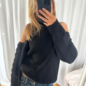 Svart stickad tröja med öppna axlar - Säljer en svart stickad tröja med unika öppna axlar. Tröjan har en lös passform och långa ärmar. Använd 2-3 gånger❤️