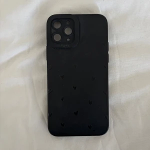 Svart mobilskal med hjärtan - Snyggt svart mobilskal iPhone 11 PRO med små hjärtan som ger en stilren och personlig touch. Perfekt för att skydda din telefon samtidigt som den ser trendig ut. Passar utmärkt för dig som vill ha en enkel men ändå unik design.