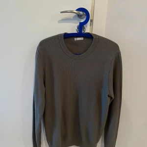 Grå stickad tröja från Cubus - Säljer en stilren grå stickad tröja från märket cubus. Tröjan har en rund halsringning och långa ärmar, perfekt för kyligare dagar. Den har en klassisk design som passar till det mesta. Perfekt för både vardag och mer uppklädda tillfällen.