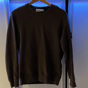 Brun sweatshirt från Stone Island - Säljer en stilren brun sweatshirt från Stone Island. Tröjan har långa ärmar och en klassisk rund halsringning. 