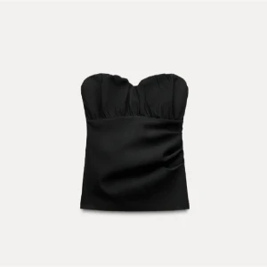 Svart axelbandslös topp - Snygg svart axelbandslös topp med en elegant och stilren design. Perfekt för en kväll ute eller en speciell tillställning. Prislappp kvar, från zara. Väldigt liten i storleken är mer som en XS/S 
