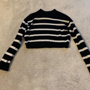 Svart och vit randig croppad tröja - Snygg svart och vit randig croppad tröja med långa ärmar. Perfekt för en trendig look. Ribbad design som ger en skön passform.