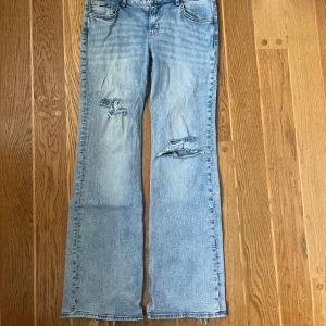 Lågmidjade bootcut jeans  - Säljer ett par ljusblå bootcut jeans med slitningar på framsidan 🤍Snygf å skön passform! Lite slitna längst ner på benen men det ger bara en cool detalj. Kan sänka pris vid snabb affär!!