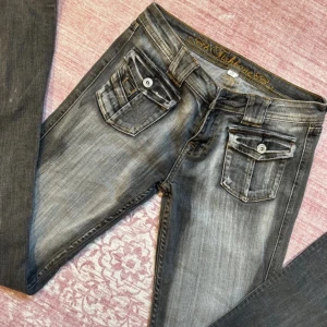 Grå jeans från Fishbone - Snygga grå jeans från Fishbone med en cool tvättad look. De har en normal passform och är utrustade med knappar och dragkedja. Perfekta för en avslappnad stil. OBS!! Avklippta längst ner för att passa någon 165 ca☺️