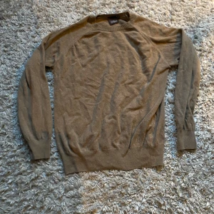 Stickad tröja Oscar Jacobson - Säljer en stilren beige tröja från Oscar Jacobson. Tröjan har långa ärmar och en rund halsringning. Perfekt för en avslappnad och snygg look. Passar bra till både jeans och chinos. Skick: 9/10