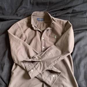 Brun skjorta från Ralph Lauren - Säljer en brun långärmad skjorta från Ralph Lauren i slim fit. Strl m, sitter perfekt på mig. Jag är 175 lång och väger 65 kg, priset kan diskuteras 