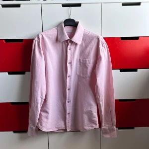 Rosa skjorta från Paul & friends - Säljer en stilren rosa skjorta från Paul & friends. Skjortan har en klassisk krage och knäppning framtill med bröstficka. Perfekt för en avslappnad men ändå uppklädd look.