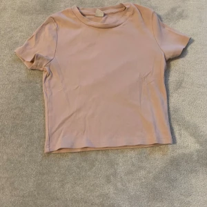Rosa ribbad t-shirt - Säljer en söt rosa ribbad t-shirt med korta ärmar. Perfekt för en avslappnad stil. Passar bra till jeans eller kjol.