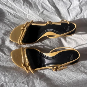 Gula klackar från Zara - Söta gula sandaler från Zara med klack och öppen tå. De är helt oanvända. Köpta för 400kr