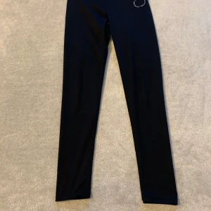 Svarta leggings med hög midja - Snygga svarta leggings med hög midja och en bred resår i midjan för extra komfort. Perfekta för både träning och avslappnade dagar. Tillverkade i ett stretchigt material som ger en tight passform.