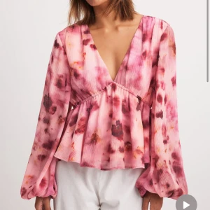 Rosa blommig blus från NA-KD - Supersöt blus i rosa toner med blommigt mönster och v-ringning. Super fin nu till sommaren💕aldrig använd och helt ny, köpte men satt inte riktigt bra på mig. Storlek 40 