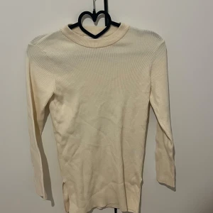 Beige ribbad långärmad tröja från Zara - Säljer en beige ribbad långärmad tröja från Zara. Tröjan har en rund halsringning och är tillverkad i ett stretchigt material som sitter snyggt på kroppen. Perfekt att styla till jeans eller kjol.