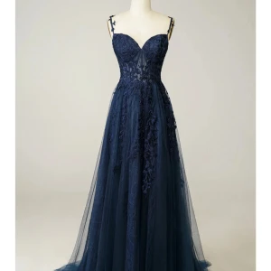 Marinblå långklänning med spetsdetaljer - Elegant marinblå långklänning med smala axelband och v-ringning. Klänningen har vackra spetsapplikationer och transparent mesh i överdelen samt utsvängd kjol i flera lager tyg. Perfekt för bal eller fest.