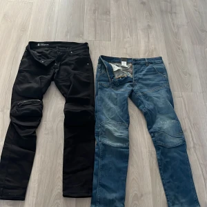 Svarta och blå jeansbyxor från G-Star RAW - Två par jeansbyxor, ett par svarta och ett par klassiskt blå från G-Star RAW. Båda har raka ben, detaljerade sömmar vid knäna och femficksdesign. Perfekta för dig som gillar stilrena och bekväma jeans med snygga detaljer. Säljer 400kr styck och 700kr för båda. Dm om intresserade!