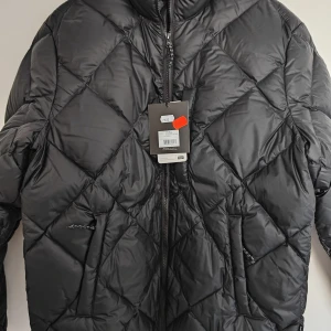 Svart quiltad pufferjacka från Peak Performance  - Säljer en svart pufferjacka från Peak Performance M storlek helt ny oanvänd ( kvitto finns kvar) med quiltat mönster och dragkedja framtill. Jackan har hög krage och två fickor med dragkedja. Perfekt för kyliga dagar och riktigt skön att bära.