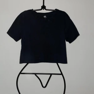 Svart croppad t-shirt från lager 157 - En enkel svart croppad t-shirt från lager 157 i 100% bomull. T-shirten har rund halsringning och korta ärmar, perfekt för en avslappnad stil.