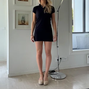 Marinblå pikéklänning från Brandy Melville - Säljer en marinblå kort pikéklänning från Brandy Melville. Klänningen har krage, korta ärmar och knappar framtill. Den är figurnära.