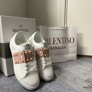 Valentino Garavani vita sneakers med rosa nitar - Säljer Valentino sneakers, köpte här på Plick och va för små, vill bara få de sålda så priset är diskuterbart! Kartong och påse sol de köptes i medföljer!💞💞