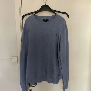 Ljusblå tröja från Polo Ralph Lauren - Säljer denna ljusblå stickad tröja från Ralph Laurent. Tröjan den klassiska broderade loggan på bröstet. Slim fit-modell som passar perfekt till sommaren.