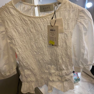 Somrig topp - Vit somrig topp med puffärm och smock i midjan. Aldrig använd+ lapp kvar