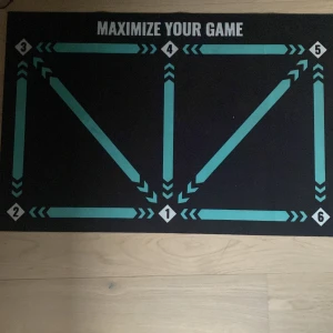 Maximize Your Game - En matta med texten 'Maximize Your Game' och numrerade sektioner från 1 till 6. Perfekt för att organisera eller spela olika spel, träna strategi eller öva färdigheter. Passar unga vuxna och ungdomar som gillar spel och utmaningar.