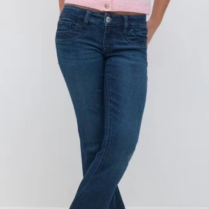 Mörkblå lågmidjade jeans  - Säljer ett par klassiska mörkblå jeans med normal passform och raka ben. Jeansen har fem fickor, knapp- och dragkedjegylf samt diskreta sömmar. Perfekta för en stilren och enkel look.