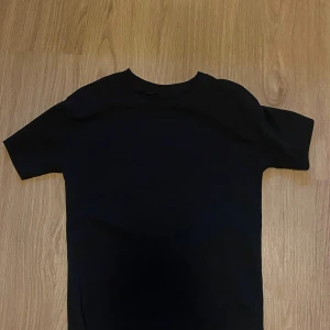 Svart t-shirt från D.M.D by denim day - En klassisk svart t-shirt från D.M.D by denim day. T-shirten har rund halsringning och korta ärmar, perfekt för en enkel och stilren look. Tillverkad i mjuk bomull för skön komfort hela dagen.