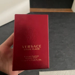 Versace Eros Flame Eau de Parfum 50ml - Versace Eros Flame Eau de Parfum i en lyxig röd glasflaska med guldigt lock. Flaskan har Versaces ikoniska Medusa-huvud och geometriskt mönster. Doften är intensiv och maskulin, perfekt för dig som gillar exklusiva parfymer.